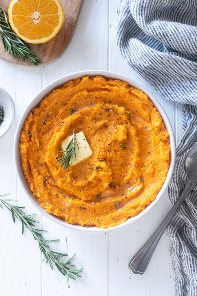 Mashed sweet potatoes with pat of butter and chopped rosemary