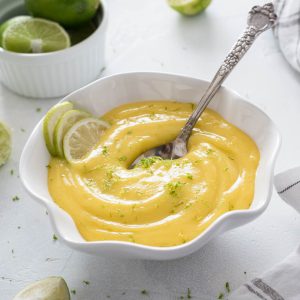 Bowl of lime curd with spoon buried in the middle