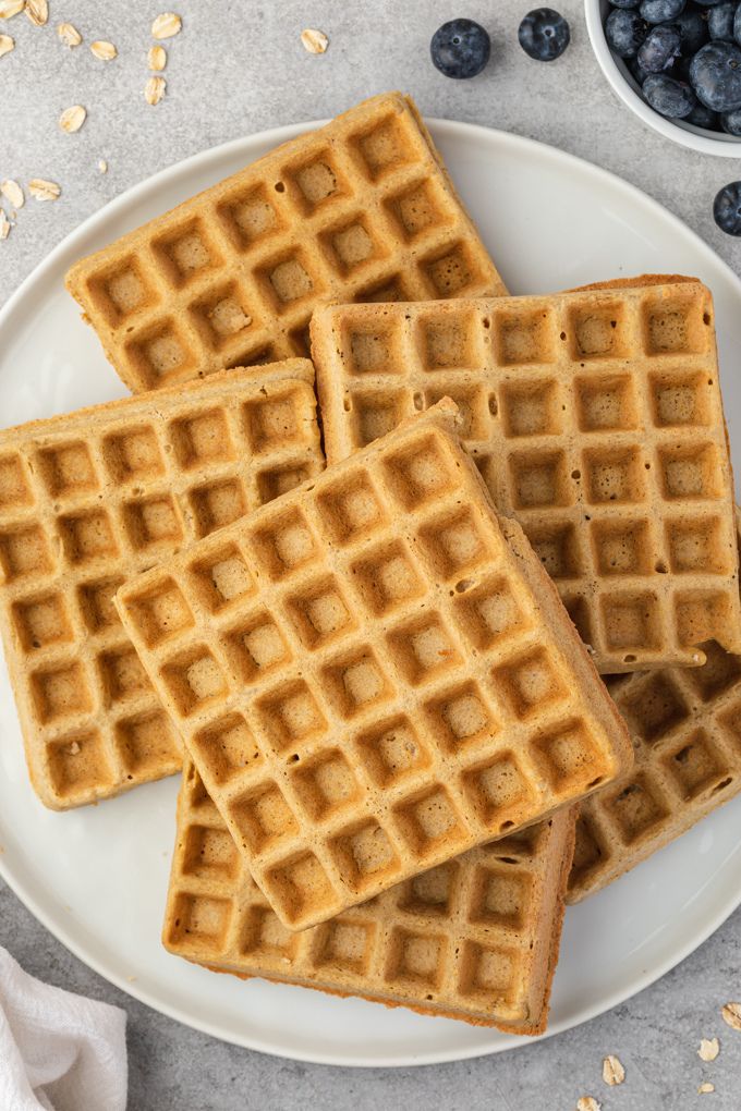 Oat flour waffles piled on a white plate