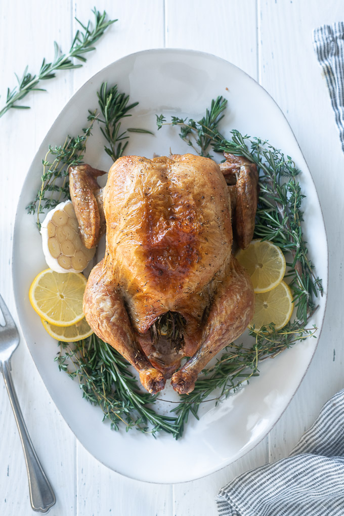 Easy Roasted chicken on a platter with lemon, garlic and rosemary