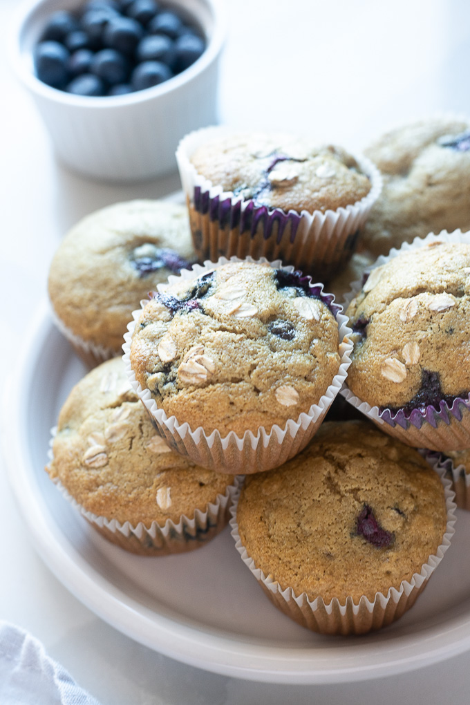 Blueberry oat muffins piled on a white plate