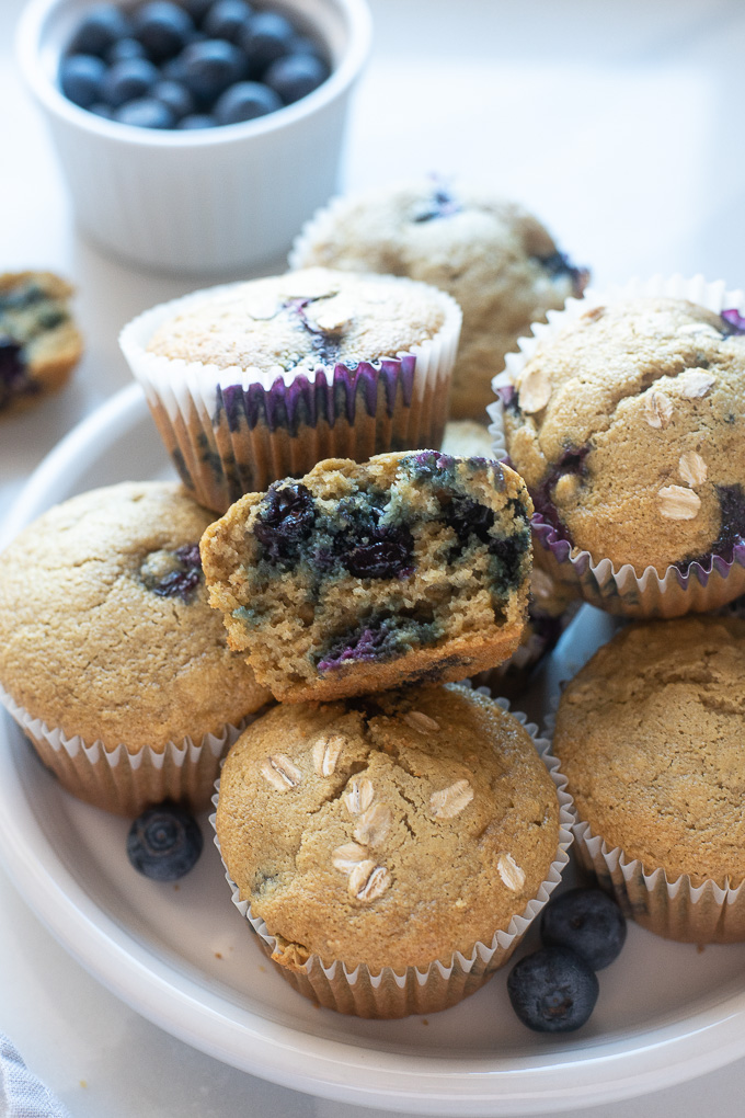 Healthy blueberry oatmeal muffins on a plate with top muffin cut in half