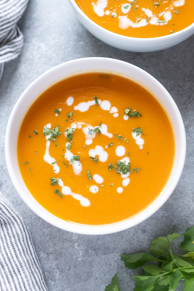 Carrot soup in a bowl with coconut milk and cilantro on top