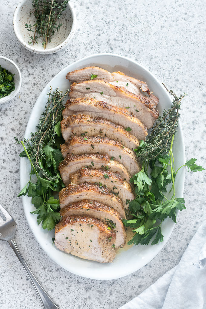 Pork loin roast on a platter with fresh parsley