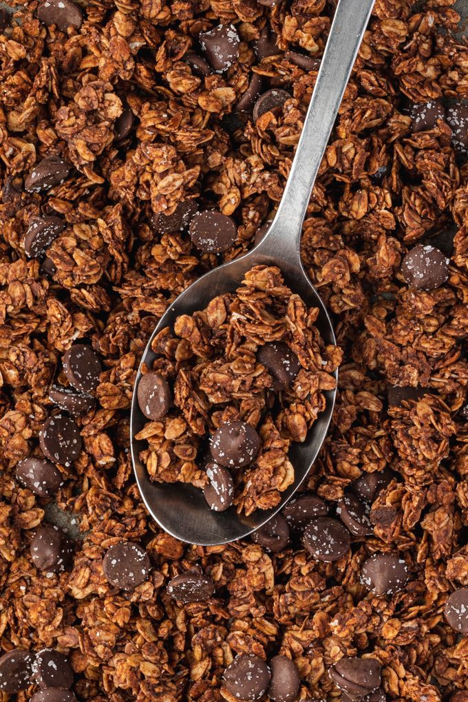 Spoonful of chocolate granola on a sheet pan