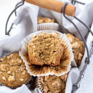 Banana oat flour muffins in basket with top muffin cut in half.