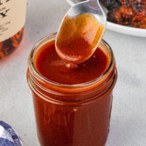 Spoon drizzling bourbon bbq sauce into a jar