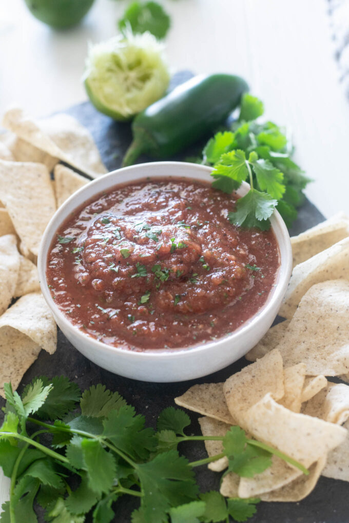 Restaurant style salsa in a bowl with chips and cilantro around it