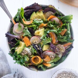 Spring mix salad in a bowl with serving spoon