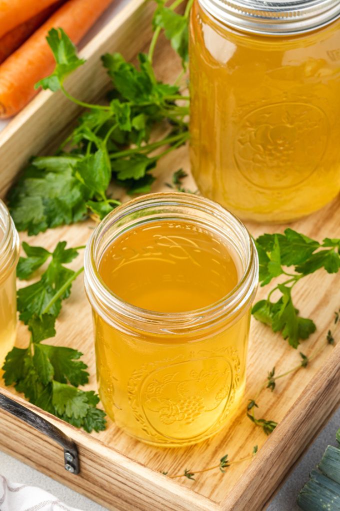 Jars of homemade vegetable stock on wooden serving tray