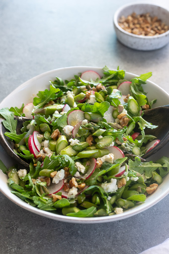 Cold asparagus salad tossed in a white bowl