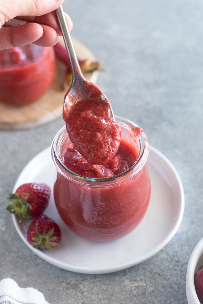 Spoonful of rhubarb and strawberry jam over a jar