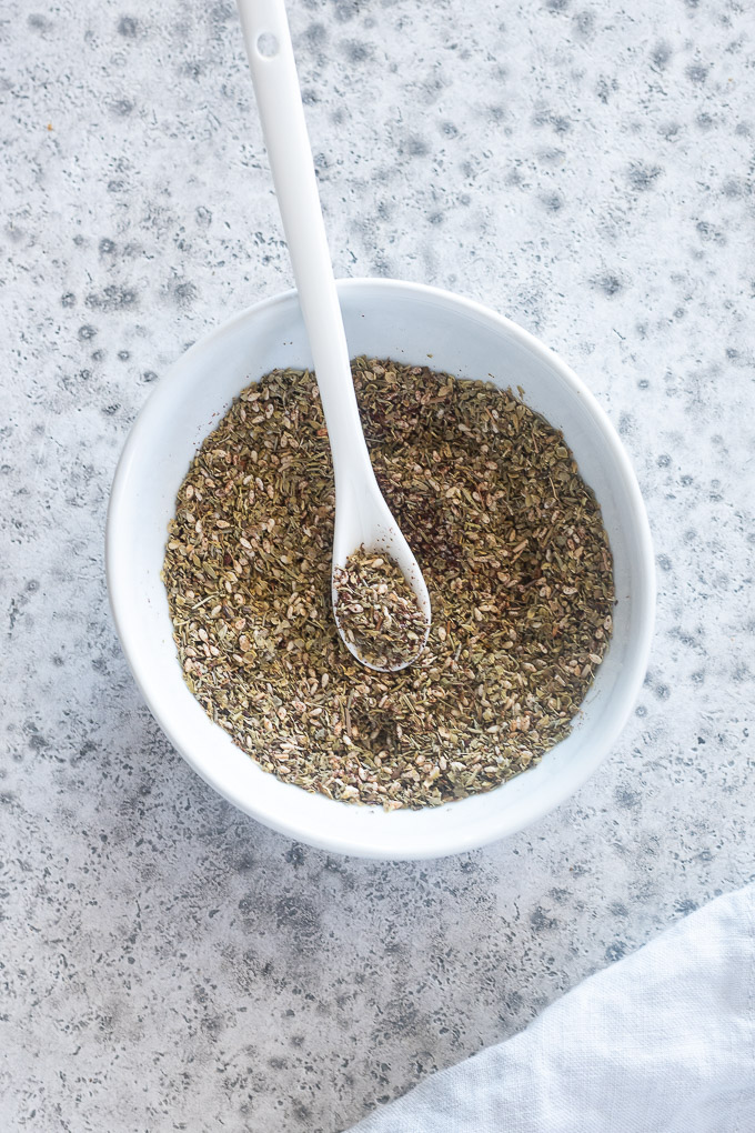 Za'atar spice in a white bowl with a spoon