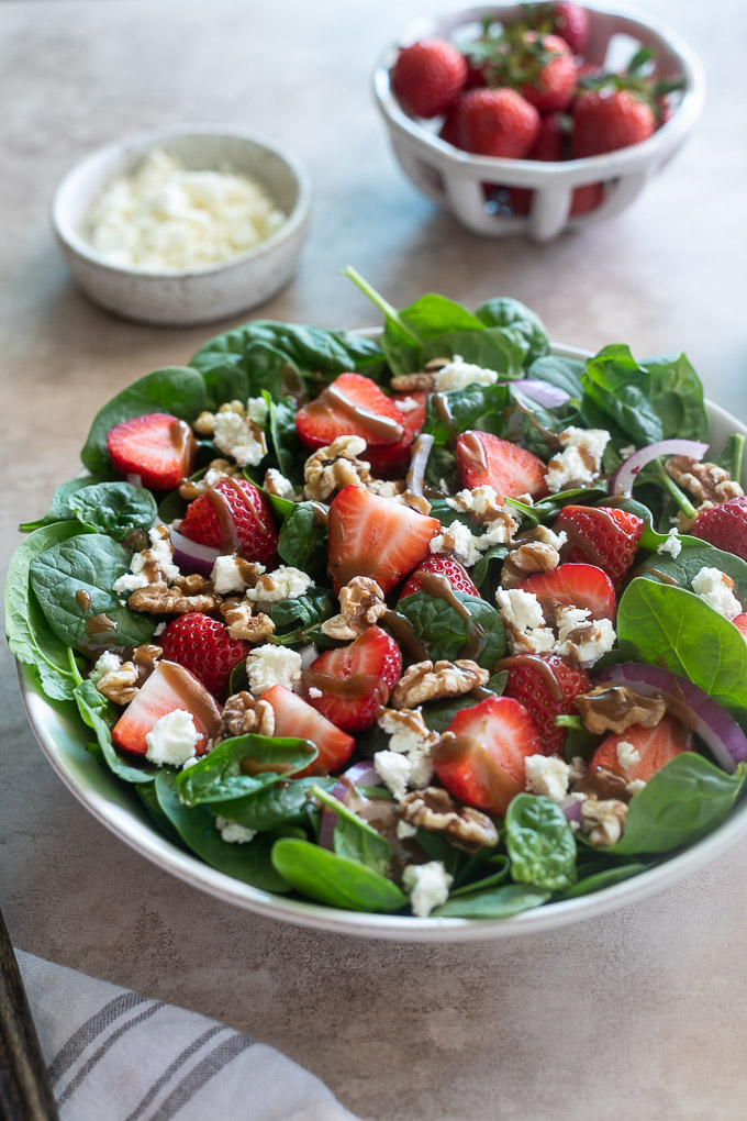Spinach and strawberry salad in a white serving bowl