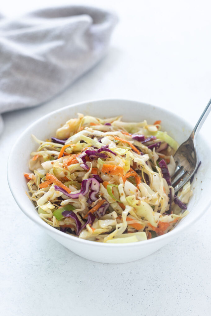 Vinegar coleslaw in a bowl with a fork digging in