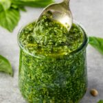 Basil pesto in a jar with spoon digging in