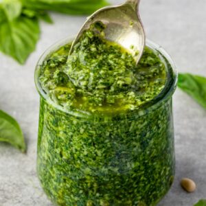 Basil pesto in a jar with spoon digging in