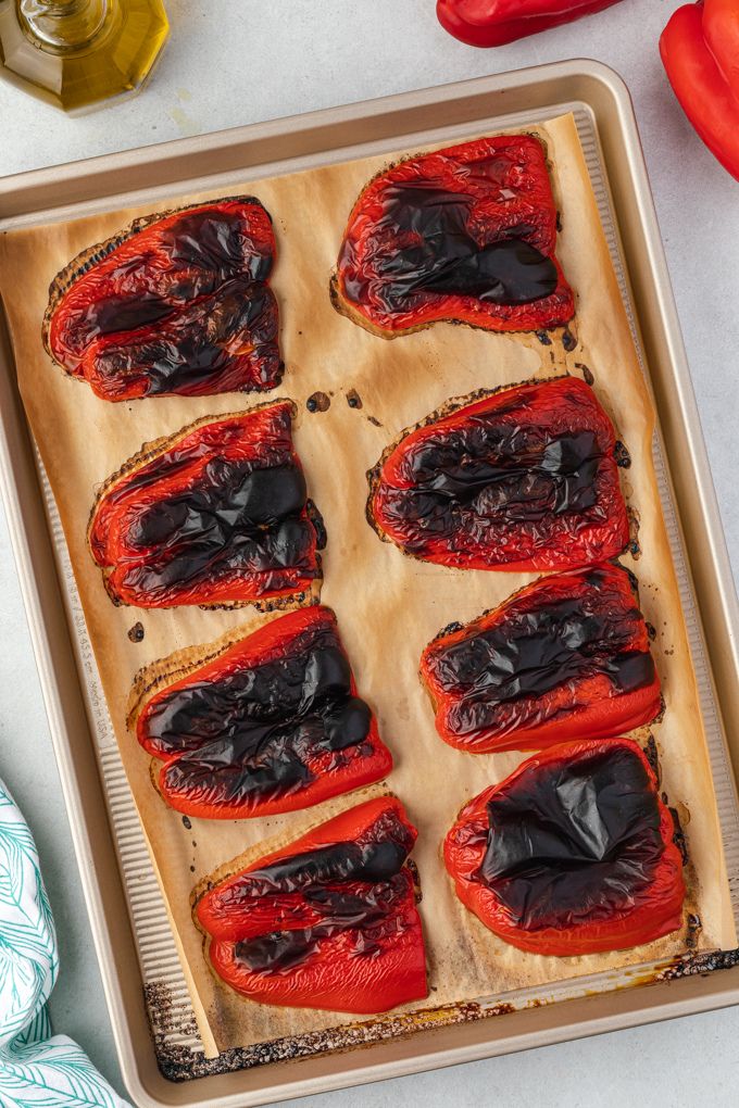 Roasted bell peppers on a parchment lined baking sheet