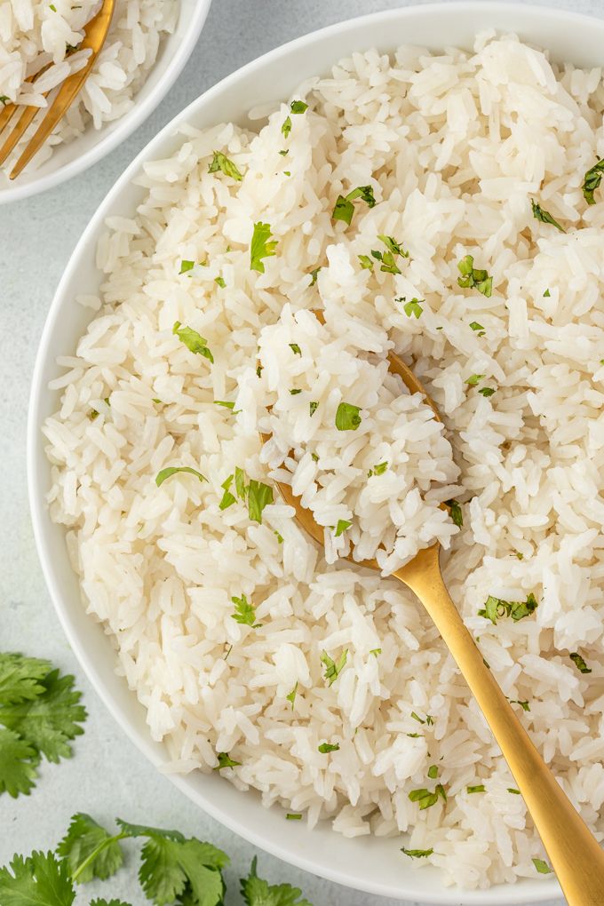 Coconut rice in a white bowl with cilantro and a spoon