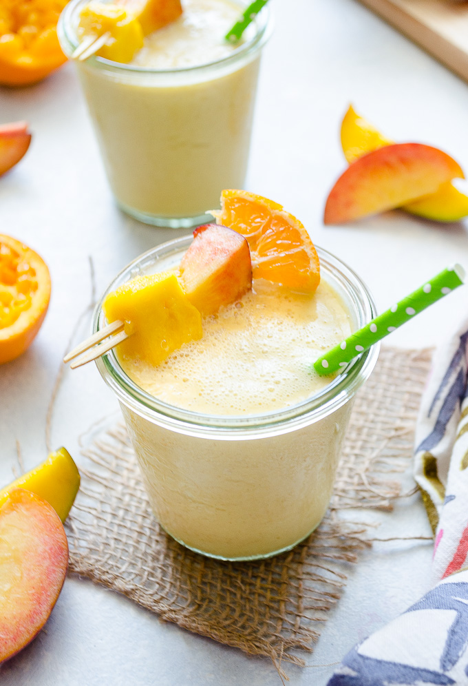 Peach mango smoothie in a jar with a straw