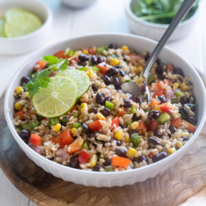 Southwest brown rice salad in a bowl with serving spoon digging in