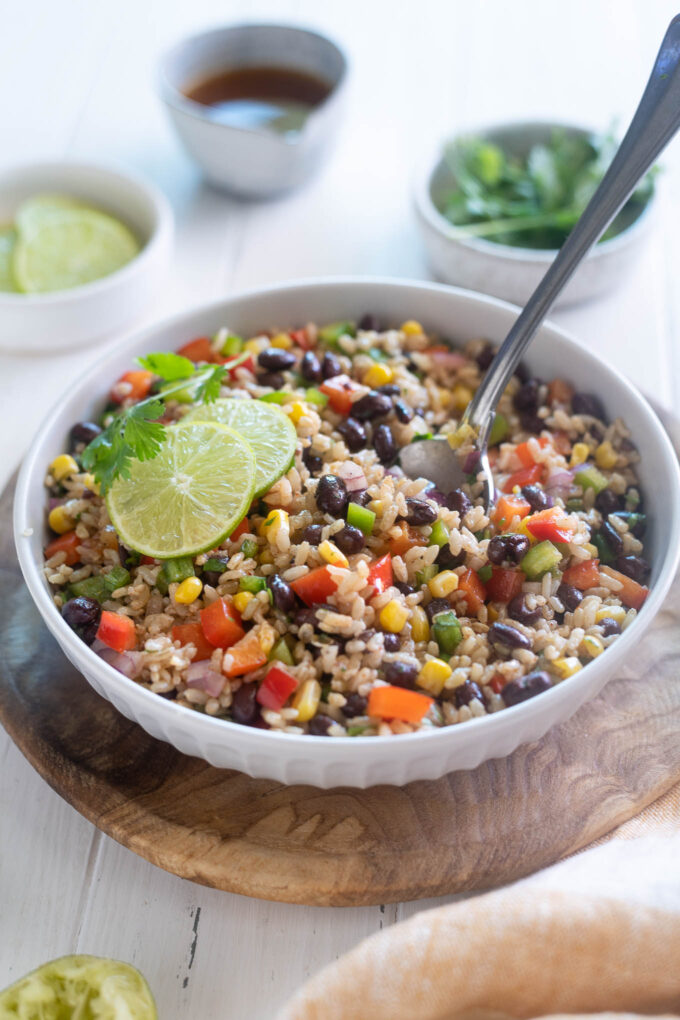 Southwest brown rice salad in a bowl with serving spoon digging in