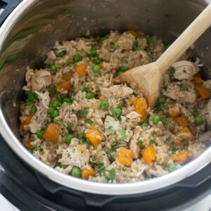 Chicken and rice in the instant pot with wooden spoon digging in