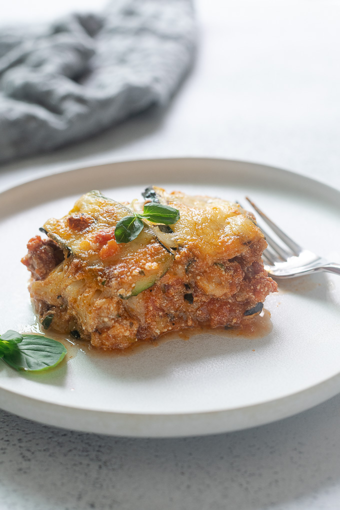 Serving of zucchini lasagna on a plate with basil