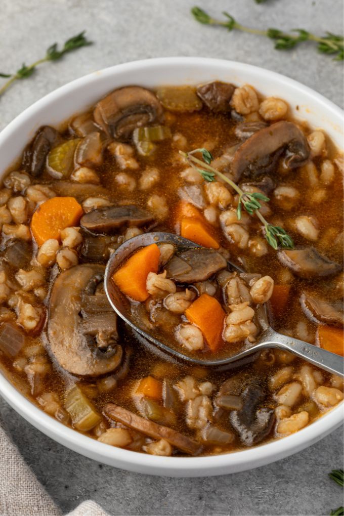 Bowl of vegetarian mushroom barley soup with spoon digging in