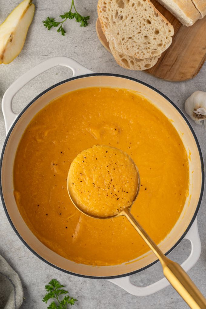 Roasted butternut squash soup in a dutch oven in a ladle