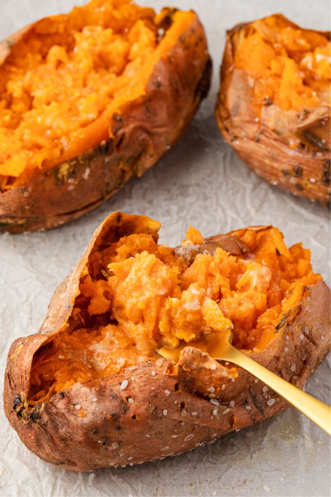 Oven baked sweet potatoes with a fork fluffing one up