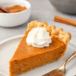 Slice of pumpkin pie from scratch on a plate with whipped cream