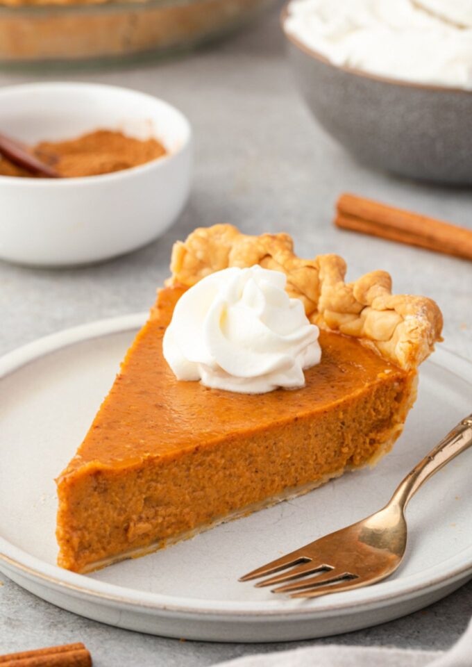 Slice of pumpkin pie from scratch on a plate with whipped cream