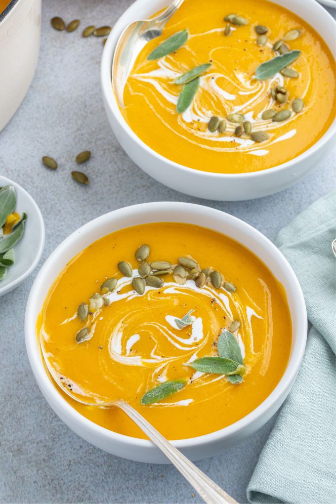 Bowls of roasted pumpkin apple soup with a spoon digging in