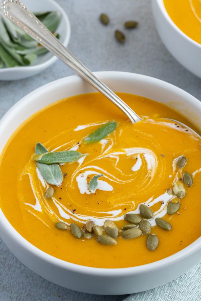 Roasted pumpkin soup in a bowl with garnishes and a spoon