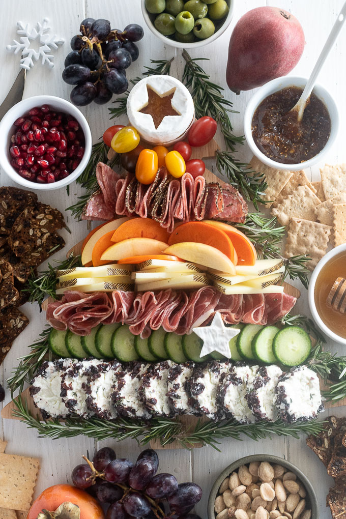 Christmas charcuterie board with crackers, jam, almonds and grapes surrounding it