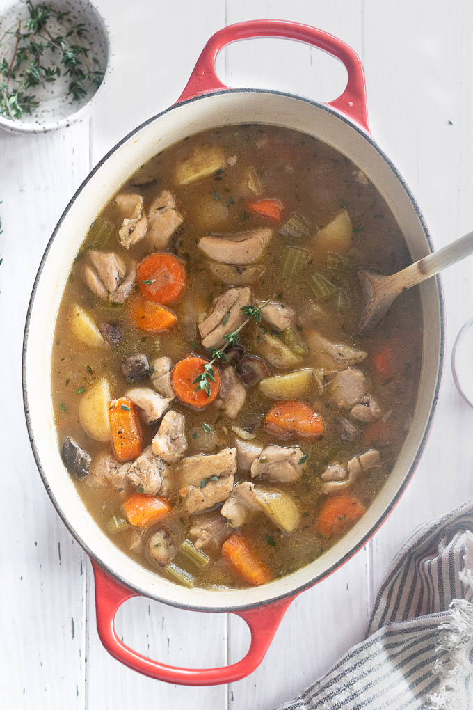 chicken stew in a dutch oven with a wooden spoon