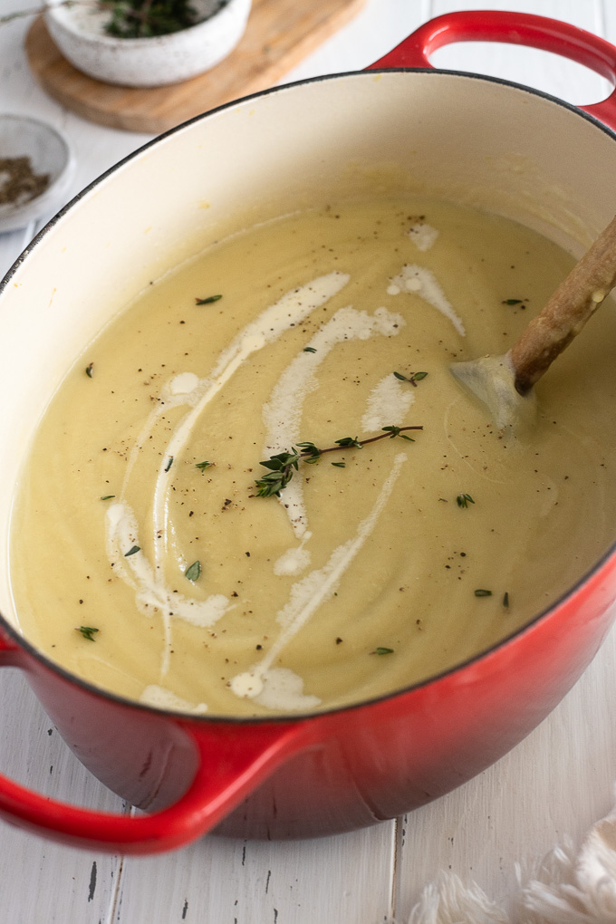 Creamy parsnip soup in a Dutch oven with cream and thyme