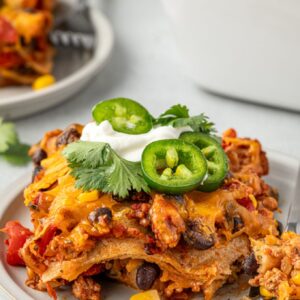 Serving of Mexican tortilla casserole topped with sour cream and jalapeno