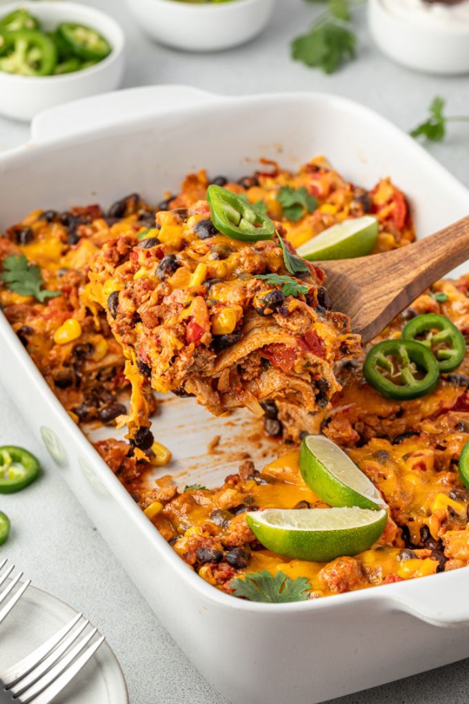 Serving of Mexican tortilla casserole being lifted out of baking dish