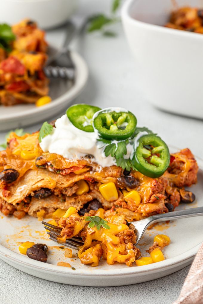 Mexican lasagna on a plate with a bite out of it