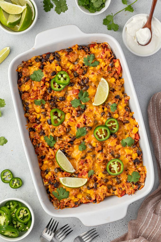 Mexican tortilla casserole in baking dish with jalapeno and lime