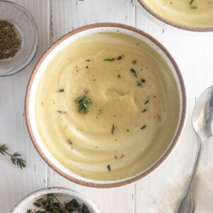 Parsnip soup in a bowl with thyme leaves