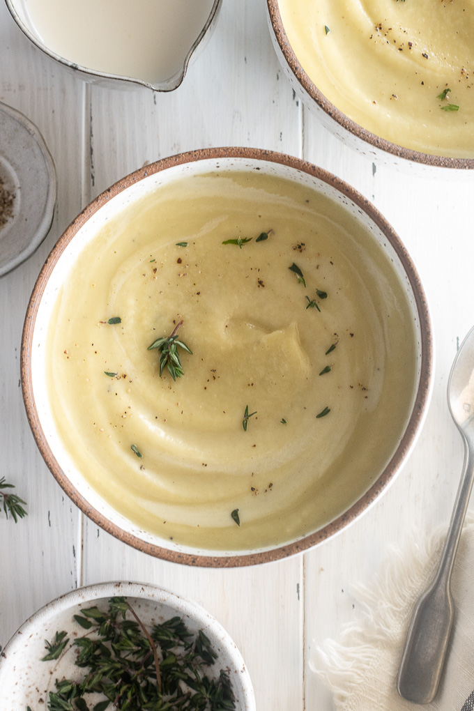 Bowl of parsnip soup with cream and thyme leaves
