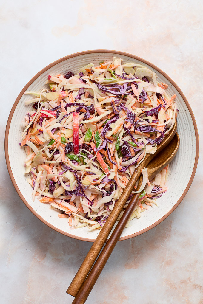 Apple fennel slaw in a serving bowl with wooden spoons