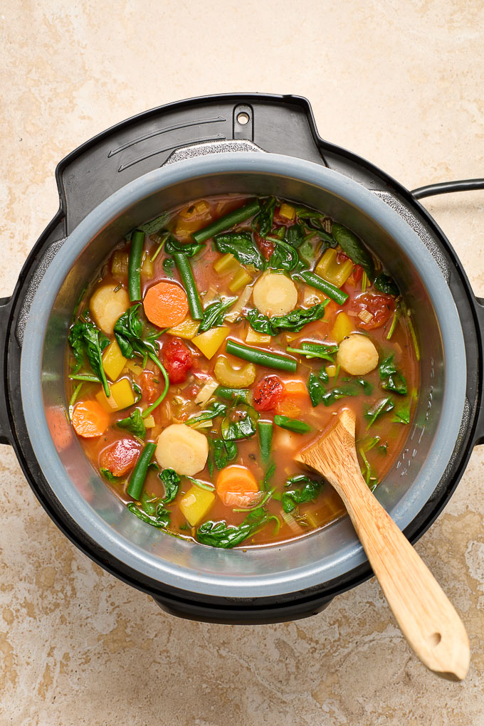 Vegetable soup in Instant Pot with a wooden spoon 