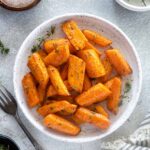 Air fryer carrots on a plate with thyme leaves