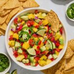 Mango avocado salsa in a bowl with a chip dunked in.