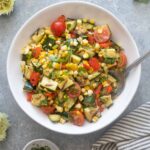 Grilled zucchini and corn salad in a bowl with serving spoon.