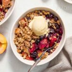 Peach blueberry crisp in a bowl with ice cream.